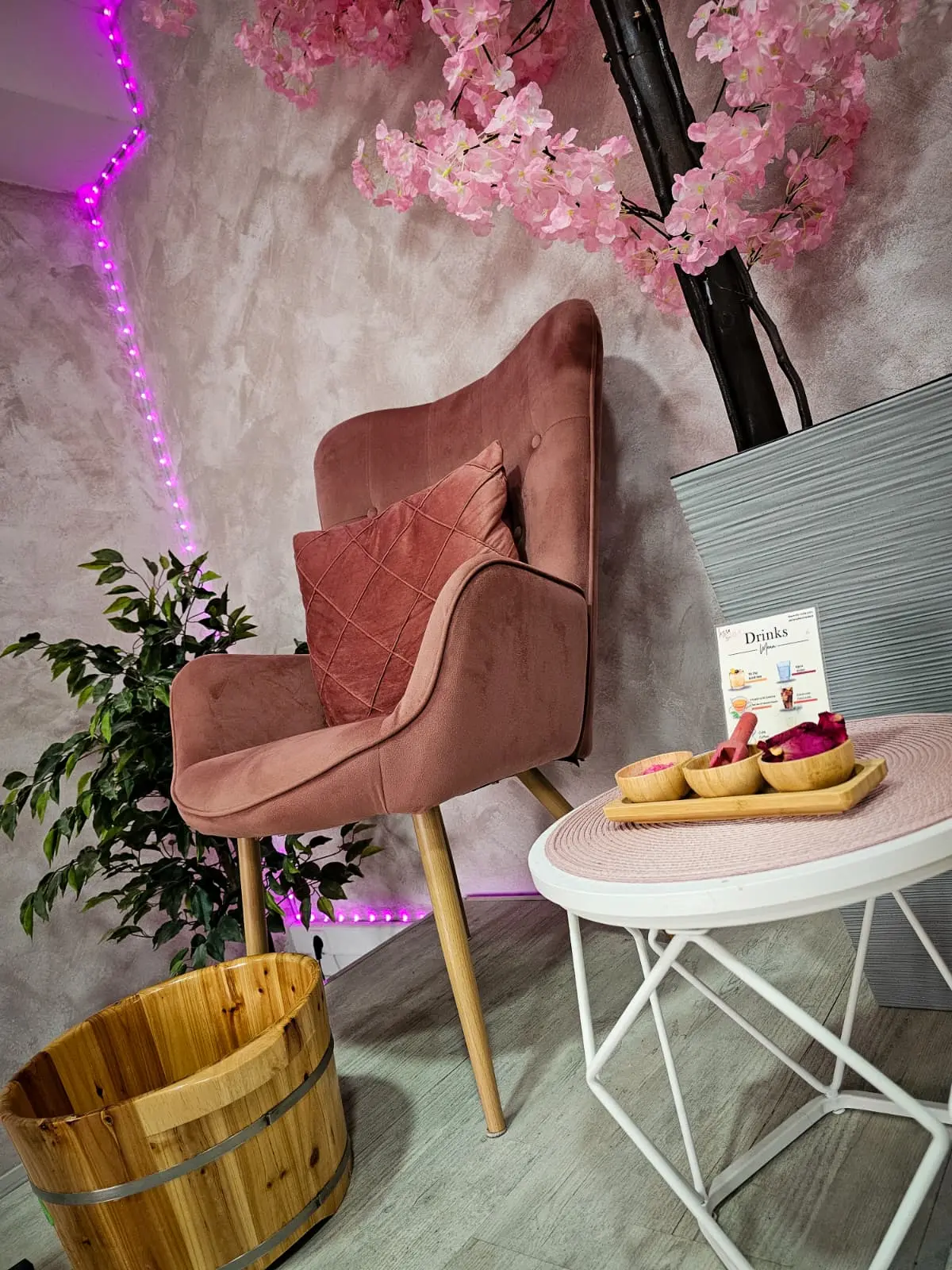 Rincón de relax del salón con sillón rosa, flores de cerezo y carta de bebidas